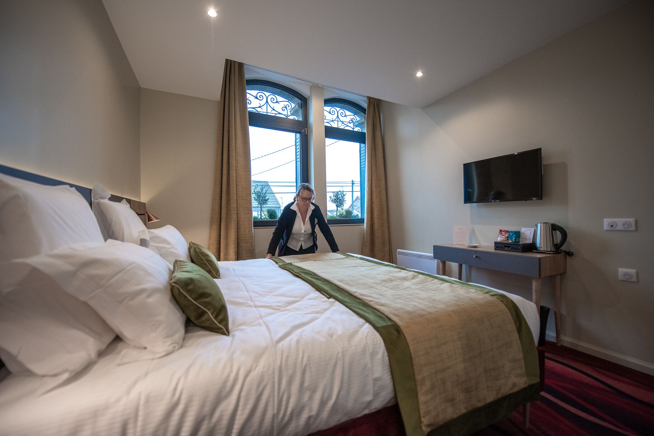 Una habitación de hotel con una cama grande, un escritorio, un televisor de pantalla plana y una ventana con cortinas.