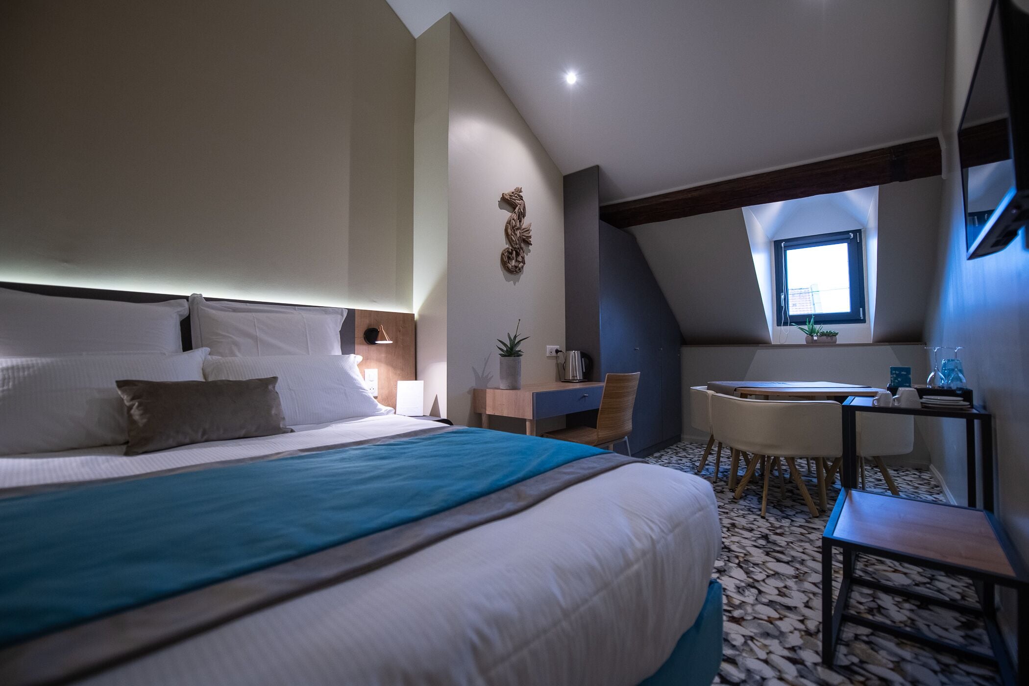 Un dormitorio con una cama grande, un escritorio, una silla, una mesita y una ventana.