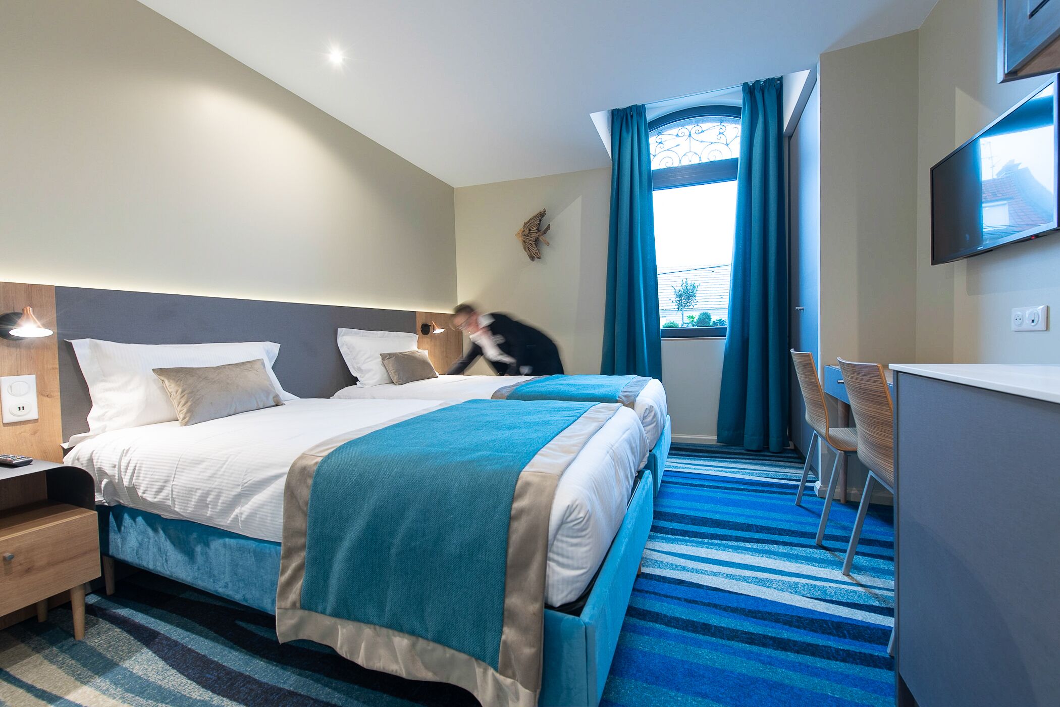 Une chambre d’hôtel avec un lit, un bureau et une chaise.