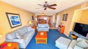 A living room with two grey sofas, a wooden coffee table, a TV, and a ceiling fan.