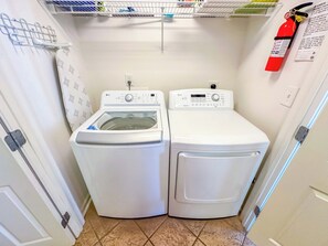 Un cuarto de lavandería con dos lavadoras blancas y un tendedero.