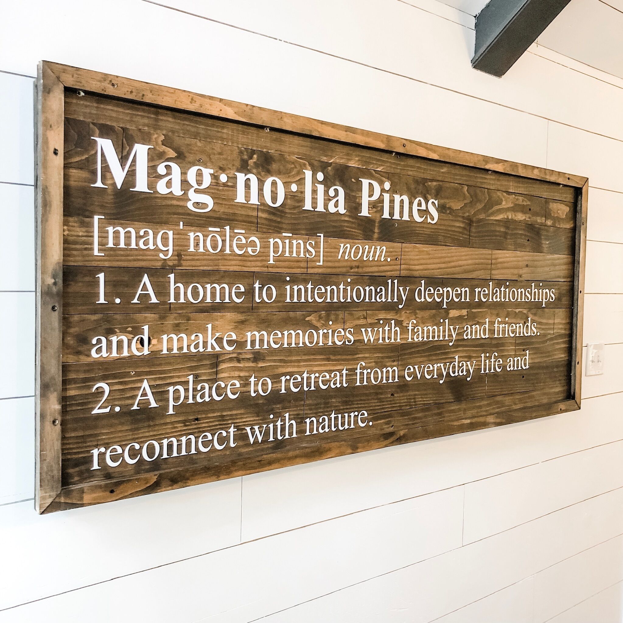 Une enseigne en bois portant le nom « Mag no bia Pines » et deux descriptions de l’endroit.