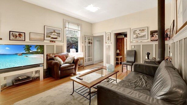 A living room with a television, leather sofas, a coffee table, and a view of a tropical beach. - Near the Ocean/Self Check-in/Out/Wifi/High Cleaning Standards  (Victoria)