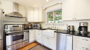A modern kitchen with stainless steel appliances, white cabinetry, and a window with a view of greenery. - Near the Ocean/Self Check-in/Out/Wifi/High Cleaning Standards  (Victoria)