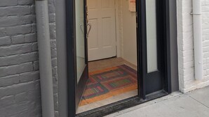 A building entrance with a black-framed door, a white door, and a colorful rug on the floor. - The Calliope, Historic Corner Apartment in the Heart of Downtown. (Savannah)