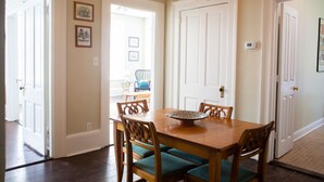 A dining room with a wooden table and chairs, a chandelier, and framed pictures on the wall. - The Calliope, Historic Corner Apartment in the Heart of Downtown. (Savannah)