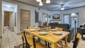 A dining area with a wooden table set for four, chairs, a chandelier, a ceiling fan, and a sofa in the background. - 2 BR and sleeper couch - close to attractions and outlet mall (Pigeon Forge)