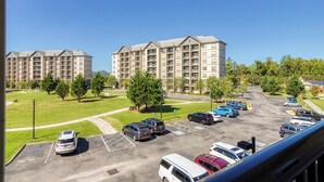 A parking lot with multiple cars, a grassy area, and two apartment buildings in the background. - 2 BR and sleeper couch - close to attractions and outlet mall (Pigeon Forge)