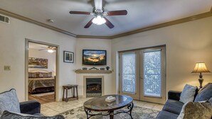 A living room with a fireplace, a ceiling fan, and a large window with blinds. - 2 BR and sleeper couch - close to attractions and outlet mall (Pigeon Forge)