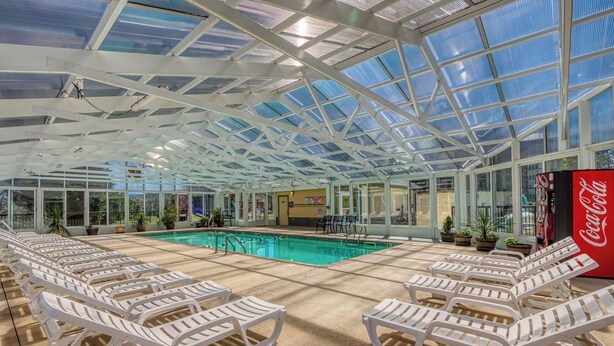 A pool area with lounge chairs, a Coca-Cola vending machine, and a glass ceiling structure. - 2 BR and sleeper couch - close to attractions and outlet mall (Pigeon Forge)