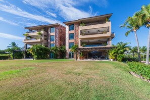 Un hotel de varios pisos con un área de estar al aire libre cubierta y un césped bien cuidado.