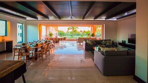 A spacious living area with a dining table, sofas, and a TV.