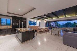 Una cocina moderna con una isla central, armarios oscuros y un ventanal grande.