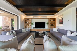 A modern living room with a large flat-screen TV, two sofas, and a coffee table.