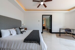 A modern hotel room with a large bed, a desk, and a ceiling fan.