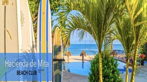 A beach club with surfboards, a pool, and palm trees.