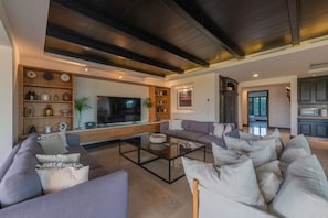 Una sala de estar moderna con un televisor de pantalla plana grande, un sofá modular y una mesa de centro.
