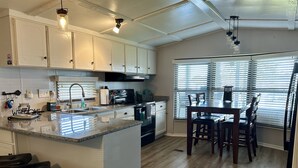 A kitchen with white cabinets, a granite countertop, and a dining area with a table and chairs.