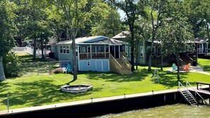 A lakeside house with a dock, a covered deck, and a fire pit.