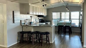 A spacious kitchen with a central island, bar stools, and a dining area with a table and chairs.