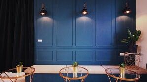 A room with a blue wall, three round tables with gold frames, and two wall-mounted lamps. - La Casa Indaco (Hengchun)