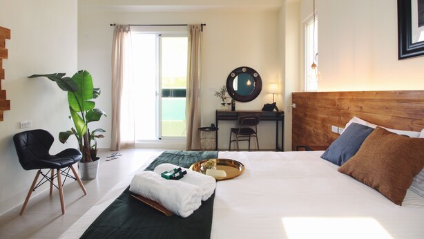 A hotel room with a bed, a desk, a chair, a potted plant, and a view of the outdoors. - La Casa Indaco (Hengchun)
