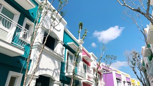 A row of colorful residential buildings with balconies, under a clear blue sky. - La Casa Indaco (Hengchun)
