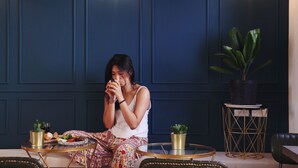 A woman sitting at a round table with a tray of food and drinks, in a room with dark blue walls and a potted plant. - La Casa Indaco (Hengchun)