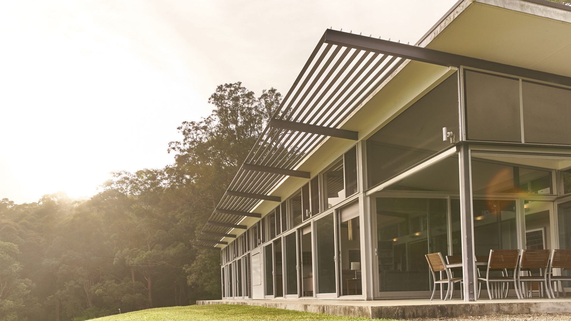 A modern building with large glass windows and a covered outdoor seating area.