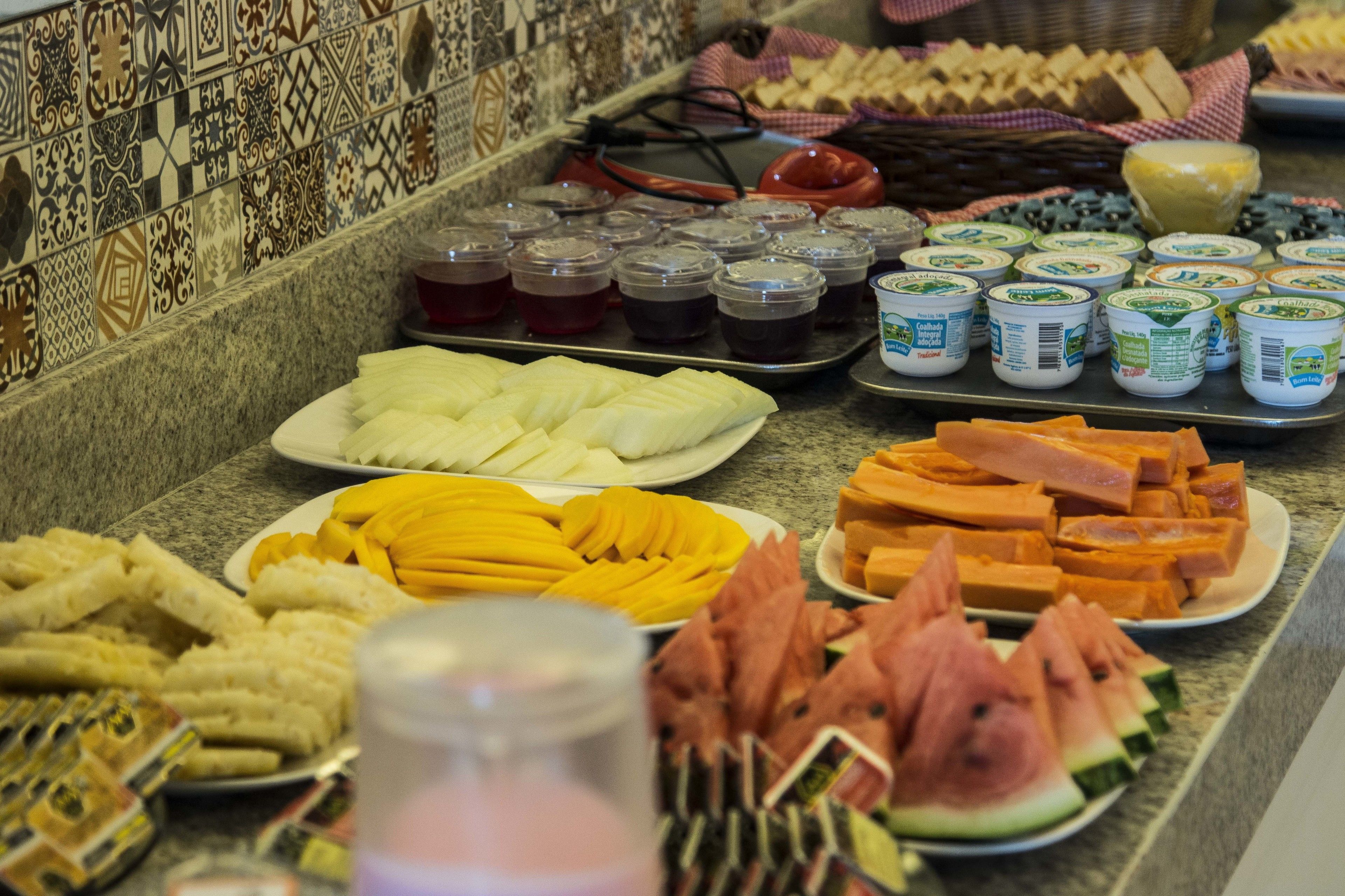 A buffet with various food items including fruits, cheeses, and condiments.