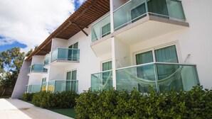 Un edificio moderno de varios pisos con balcones, ventanas amplias y un sendero adoquinado.