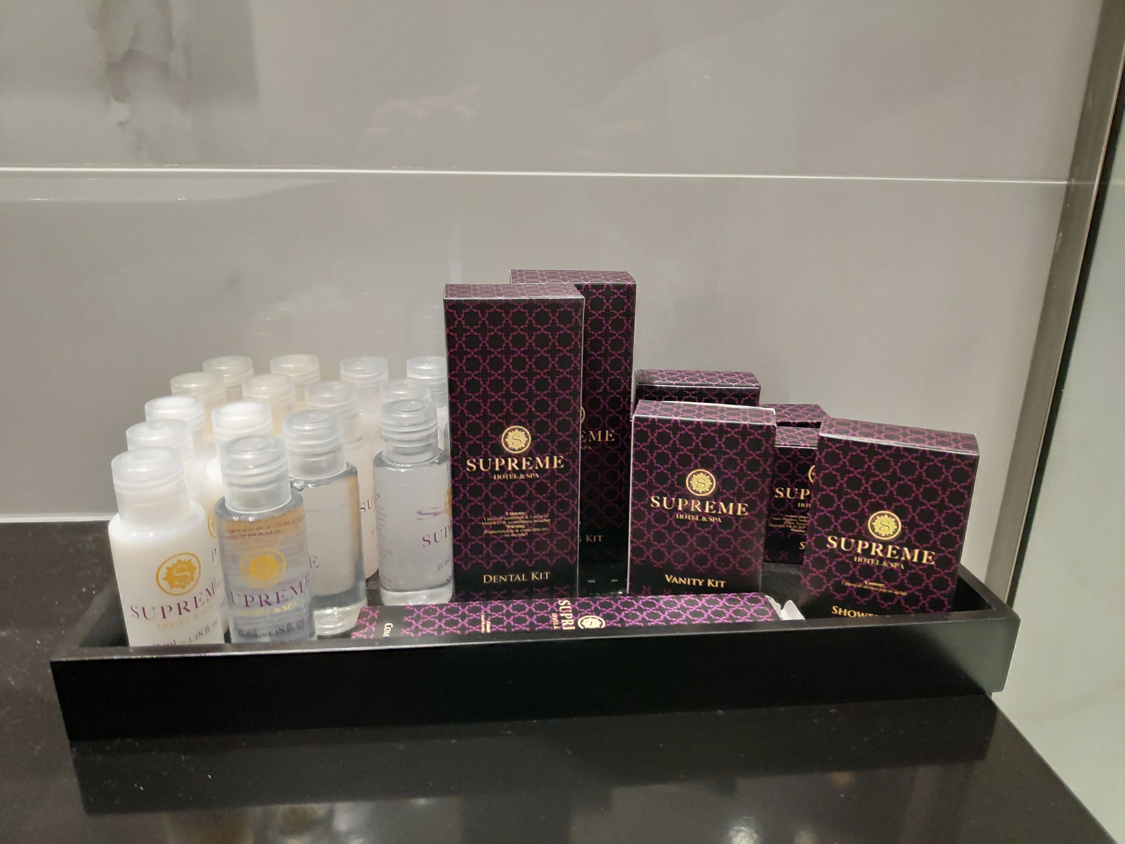 A display of Supreme Hotel & Spa products including a dental kit, vanity kit, and various bottles.