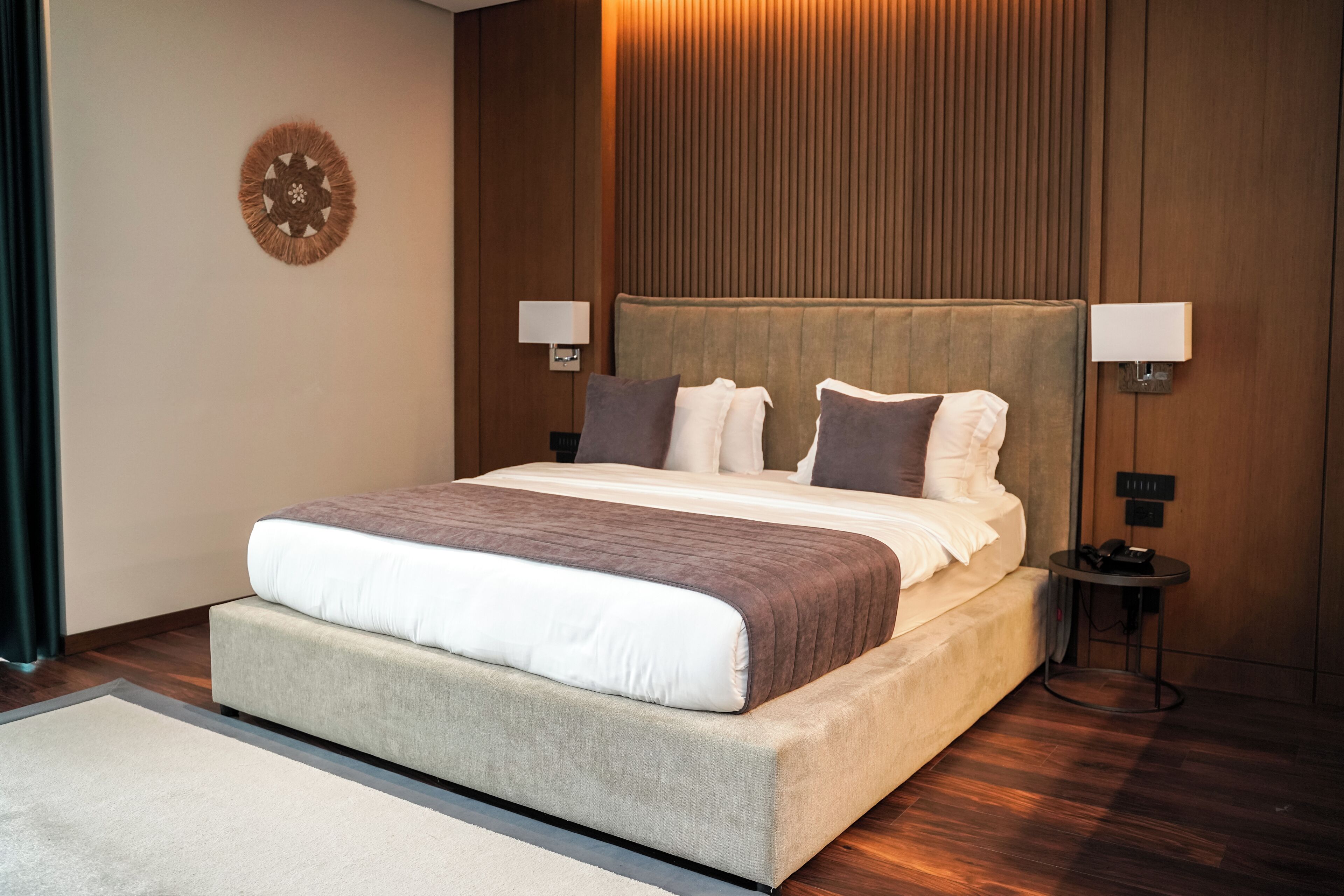 Una habitación de hotel moderna con una cama grande, dos mesitas de noche y una lámpara de pared.