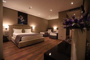 Una habitación de hotel moderna con una cama grande, un sofá más pequeño y un escritorio.
