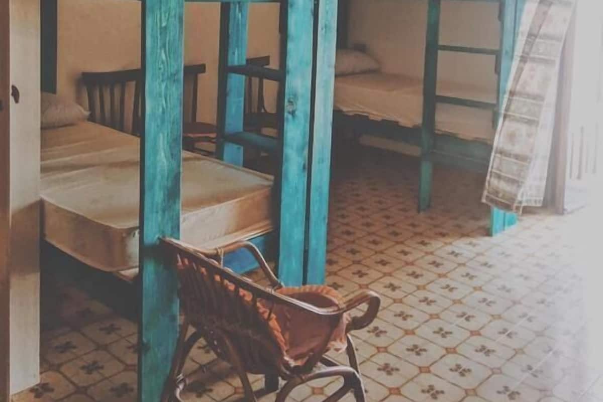 Ein Schlafsaalzimmer mit Etagenbetten, einem Stuhl und einer Pendelleuchte.
