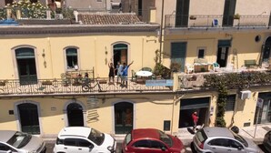 Il s’agit d’un immeuble sur lequel on peut lire une enseigne indiquant qu’il s’agit d’une auberge de jeunesse. Des voitures sont garées devant, et il y a des balcons avec des garde-corps.