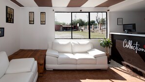 A modern living room with a white sofa, a wooden coffee table, and a large window with a view of a courtyard. - La Rinconada (Tequisquiapan)
