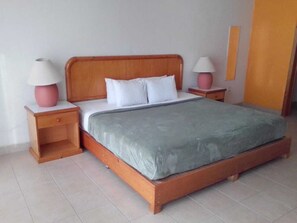 A standard hotel room with a wooden bed, two bedside tables, and a nightstand with a lamp. - La Rinconada (Tequisquiapan)