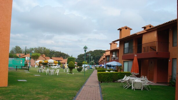 A courtyard with a paved walkway, outdoor seating, and buildings with balconies. - La Rinconada (Tequisquiapan)