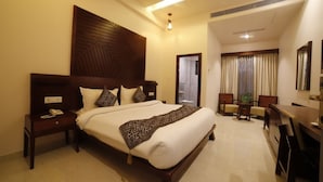 A hotel room with a large bed, bedside tables, a desk, and a chair. - Hotel  Options Lawns (Shahpura)