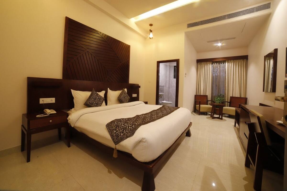 Quarto de hotel com uma cama grande, mesas de cabeceira, escrivaninha e uma cadeira.