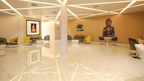 A modern lobby with a central Buddha statue, a lotus flower logo, and a calm seating area with chairs. - Hotel  Options Lawns (Shahpura)