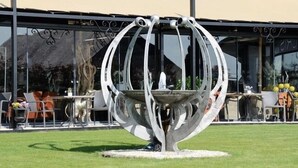 A modern outdoor seating area with a unique metal sculpture centerpiece. - Hotel Monte Cristo (Hoeselt)