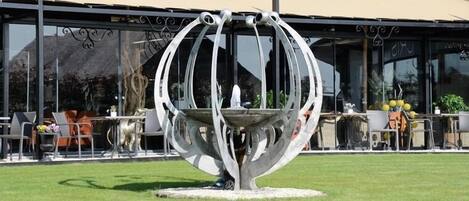 A modern outdoor seating area with a unique metal sculpture centerpiece.