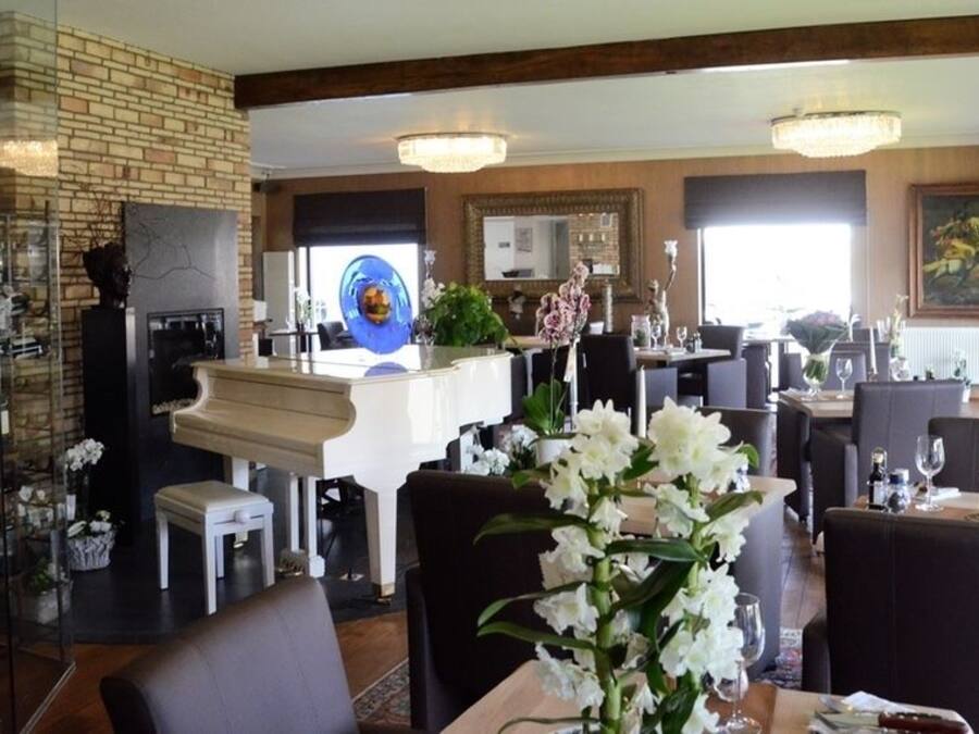 A restaurant with a brick wall, a piano, and multiple dining tables with chairs.