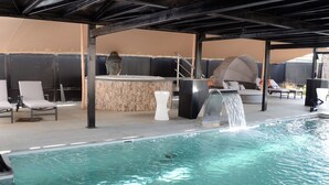 A pool area with lounge chairs, a hot tub, and a waterfall feature. - Hotel Monte Cristo (Hoeselt)