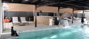 Una piscina al aire libre, sombrillas, sillones reclinables de piscina