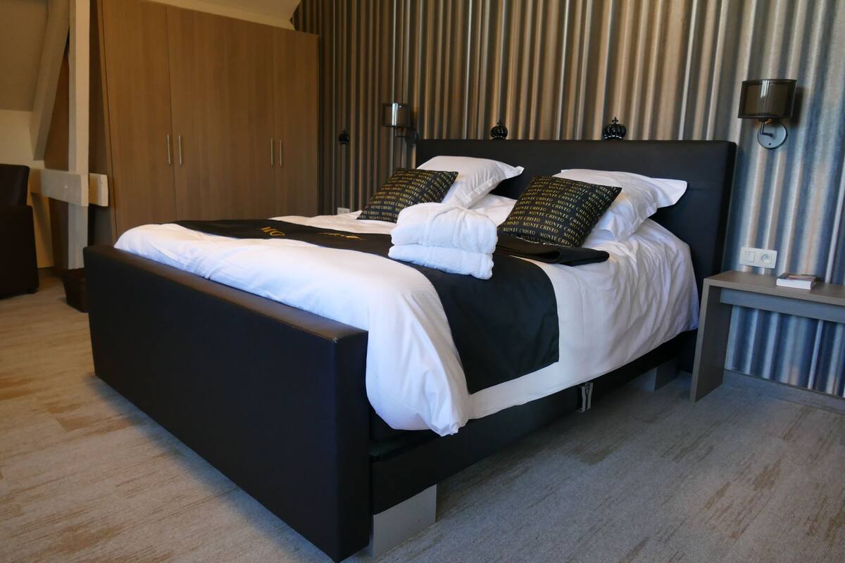 Une chambre d’hôtel moderne, dotée d’un grand lit, d’une table de chevet, d’une armoire et d’une lampe fixée au mur.