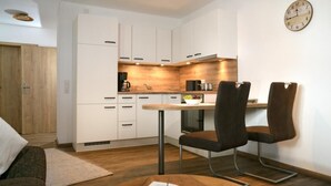 Une cuisine compacte avec des meubles blancs, un plan de travail en bois et un coin repas équipé de deux chaises.