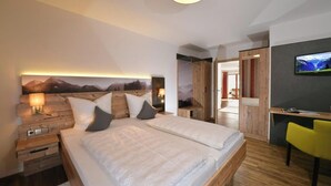 Une chambre moderne avec un grand lit, une tête de lit en bois, des tables de chevet et un téléviseur fixé au mur.